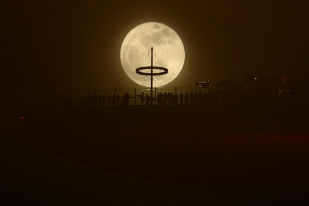 A sturgeon moon, the first Supermoon of the year, rises next to the Marina Bay Sands hotel in Singapore 